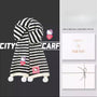 Black and white striped scarf with Hello Kitty patches on a black background, next to greeting cards and a gift box.