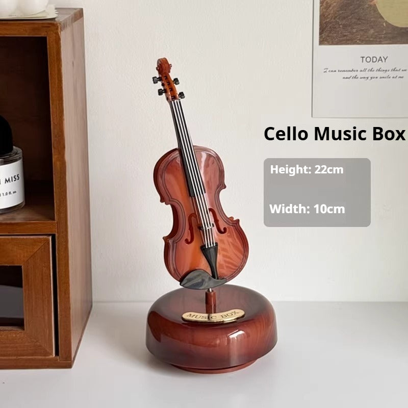 Wooden cello music box on a white surface with a wooden shelf in the background.