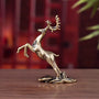 Bronze deer figurine on a wooden surface with a blurred red background