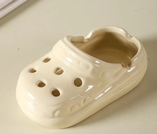 White ceramic shoe with multiple holes on a light background