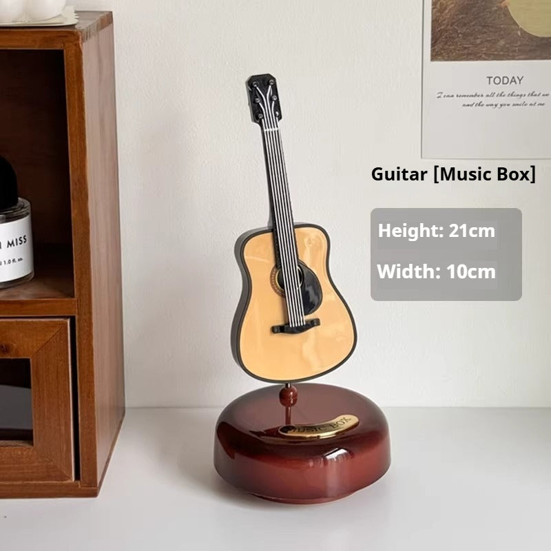 Guitar-shaped music box on a white surface with wooden shelf in the background