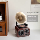 Vintage-style gramophone music box on a white surface with wooden shelf in the background