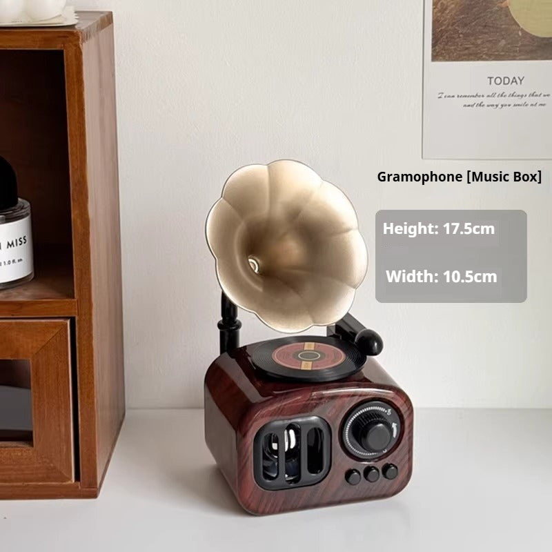 Vintage-style gramophone music box on a white surface with wooden shelf in the background
