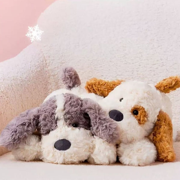 Two plush dogs sitting together on a soft surface with a pink background
