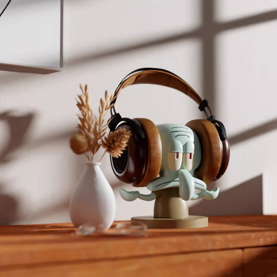 Headphones on a unique stand with a decorative figure, placed on a wooden surface.