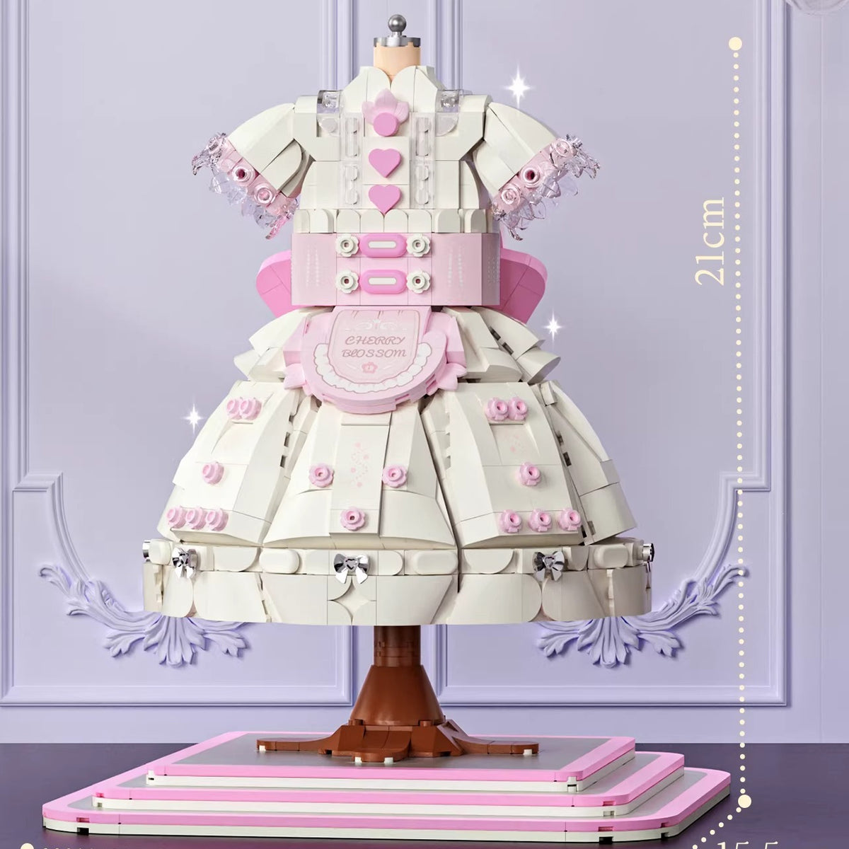 Fully assembled Lolita dress ornament displayed on a wood desk beside books, showing finished scale and layered ruffle structure