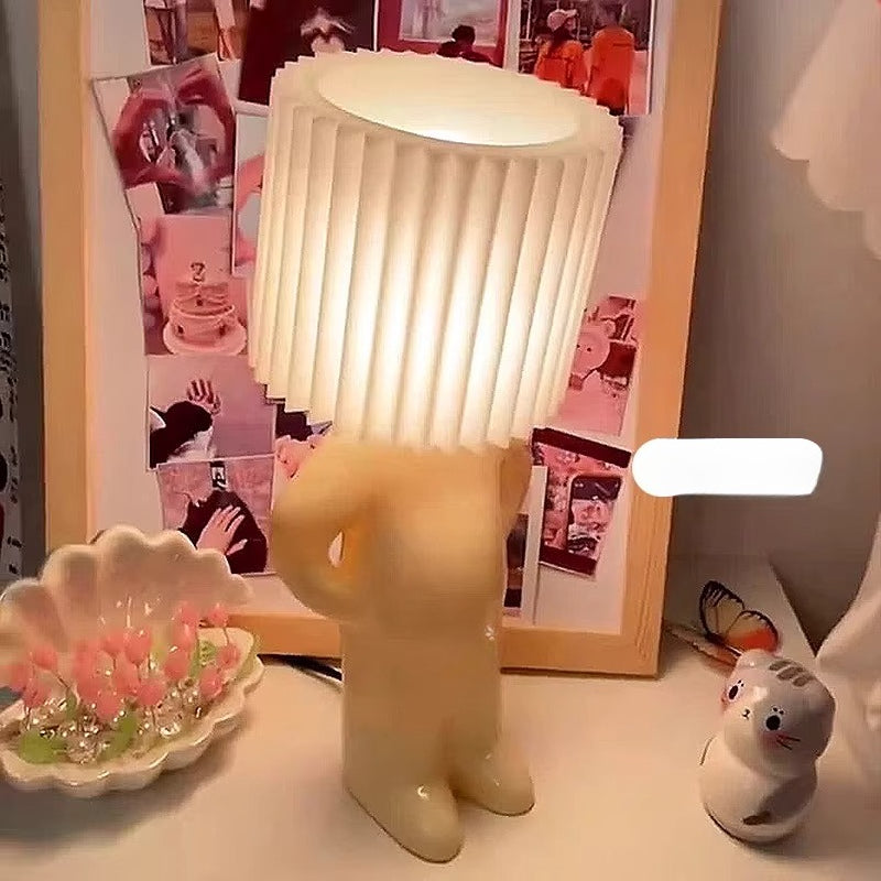 Decorative lamp shaped like a bear on a table with photos and a small figurine in the background.
