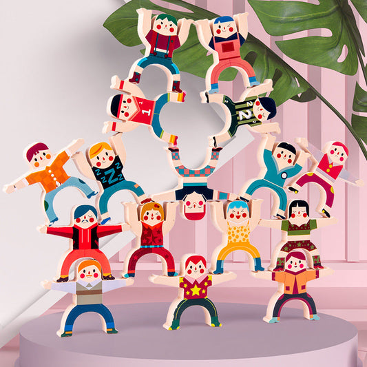 Colorful wooden figurines arranged in a pyramid formation on a white platform with a pink background.