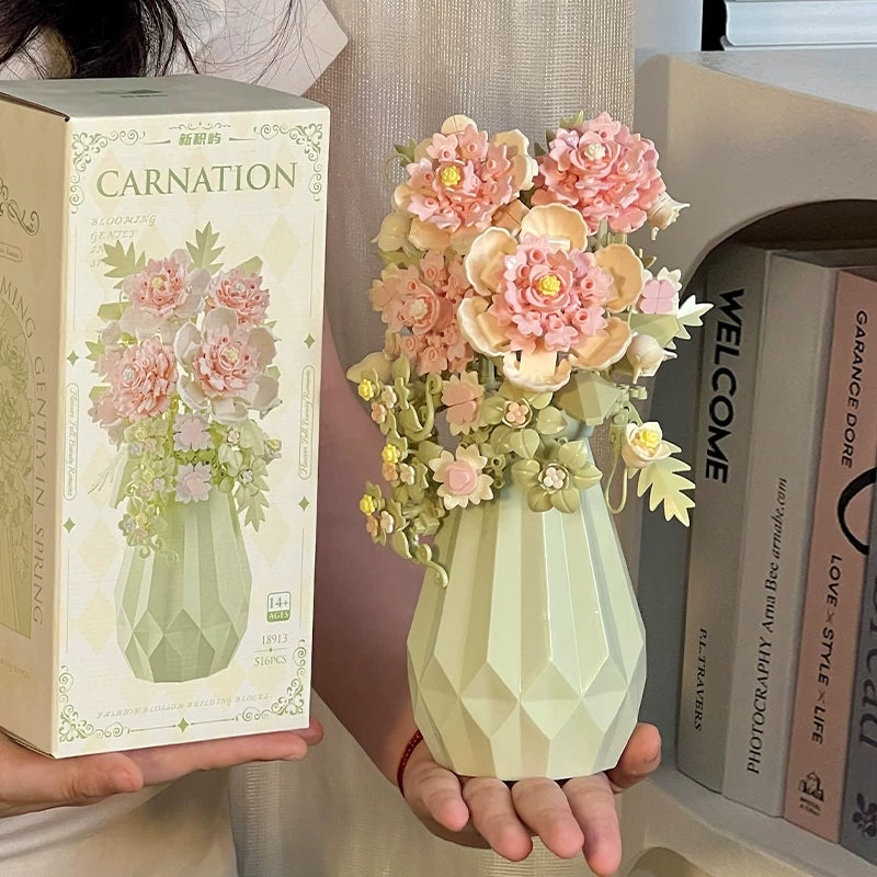Light green geometric vase with pink flowers held by a person next to its packaging.
