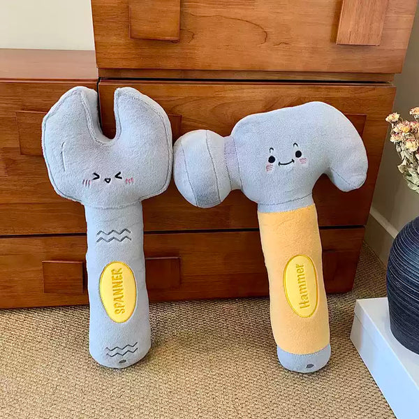 Plush toy wrench and hammer with smiling faces on a wooden floor.