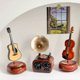 Decorative items including a guitar, gramophone, and violin on a white surface with a scenic background.