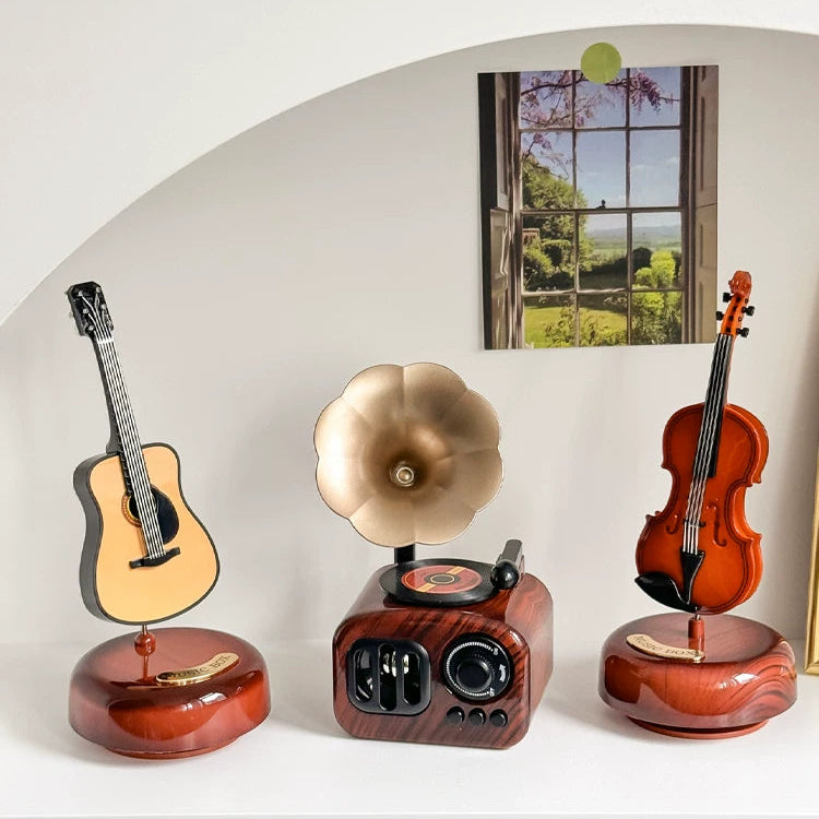 Decorative items including a guitar, gramophone, and violin on a white surface with a scenic background.