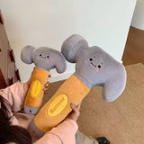 Two plush toy hammers with smiling faces held by a person on a carpeted floor.