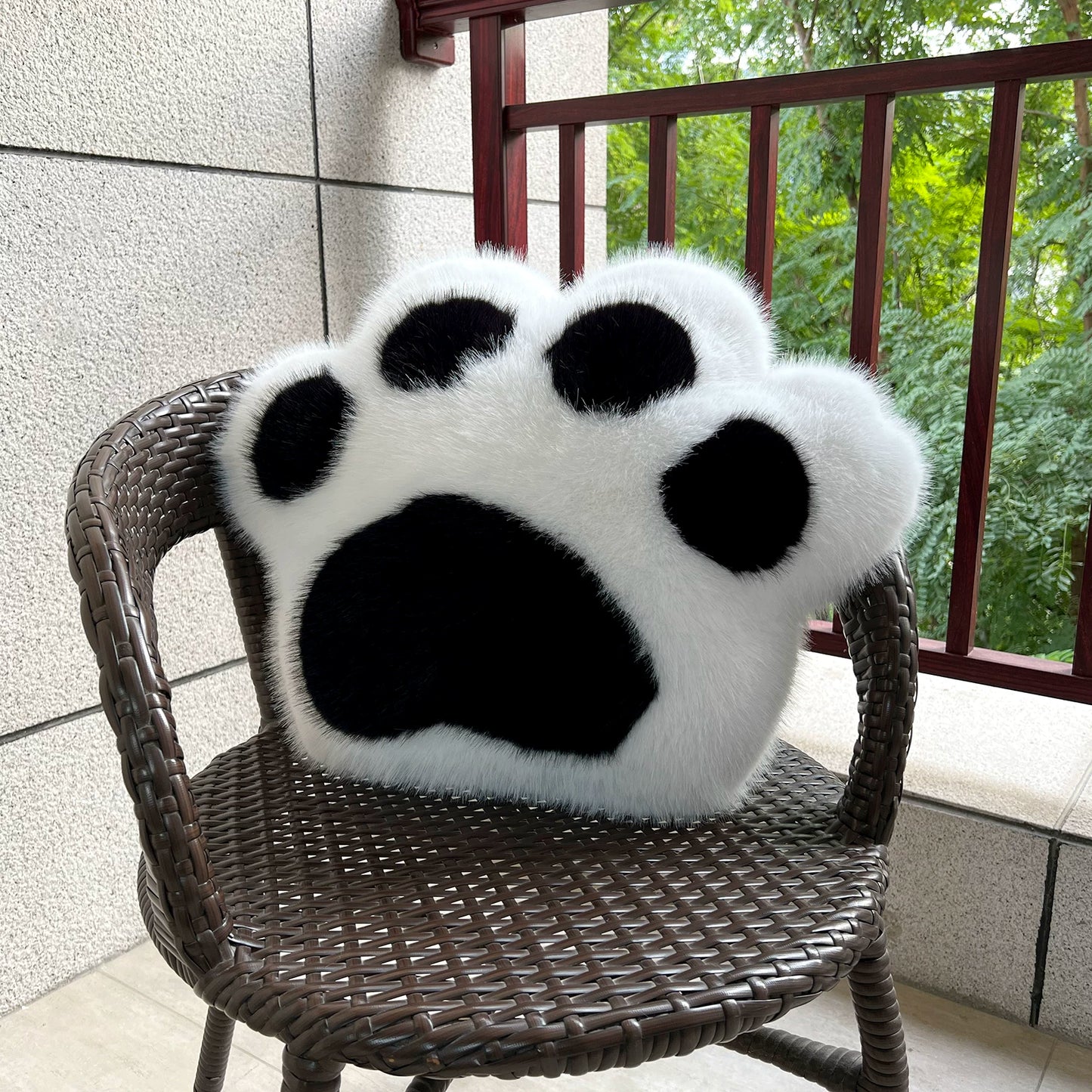 Fluffy paw-shaped pillow on a chair outdoors
