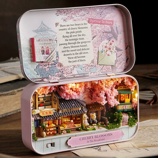 Miniature model of a cherry blossom-themed village inside an open tin box.