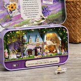 Miniature fairy garden inside a purple tin with a castle and small figures on a wooden surface.