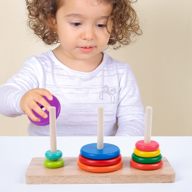 Child playing with a colorful stacking toy on a white surface.