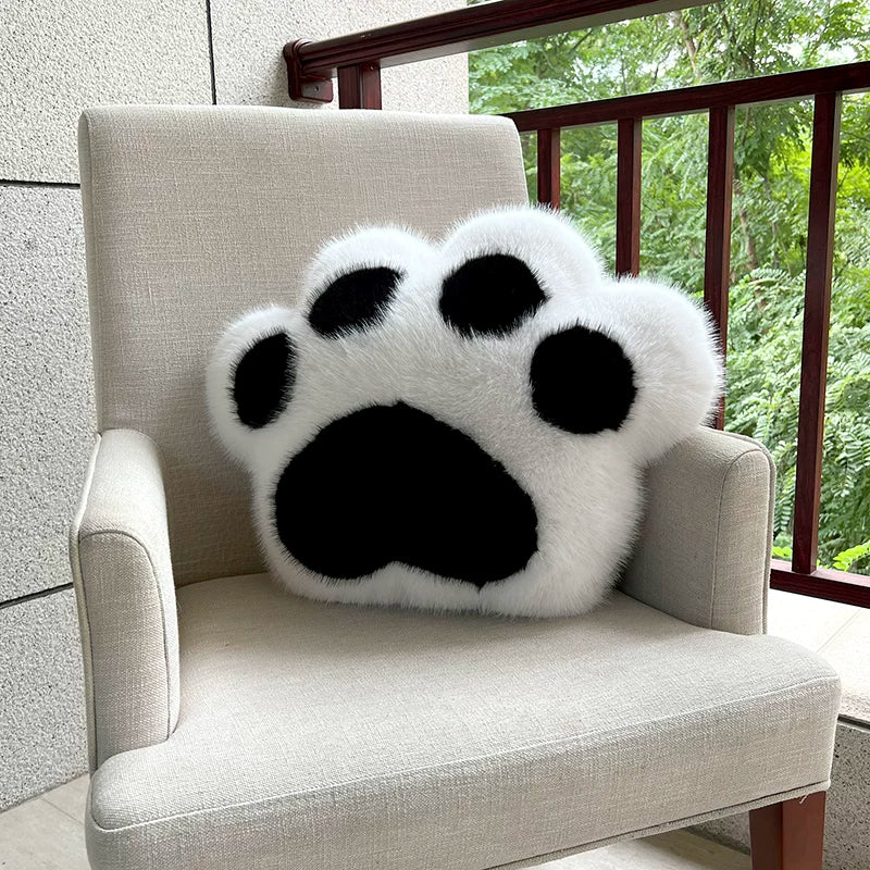 Paw print pillow on a chair with a blurred outdoor background