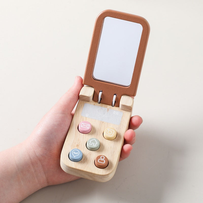 Wooden toy phone with colorful buttons held in a hand against a light background