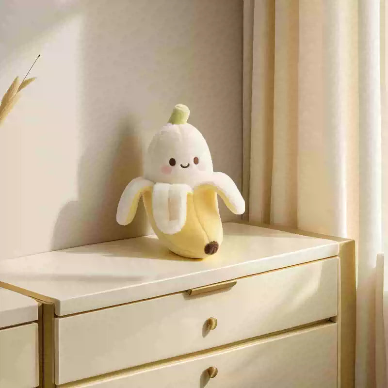 Plush toy shaped like a banana on a white dresser with a neutral background