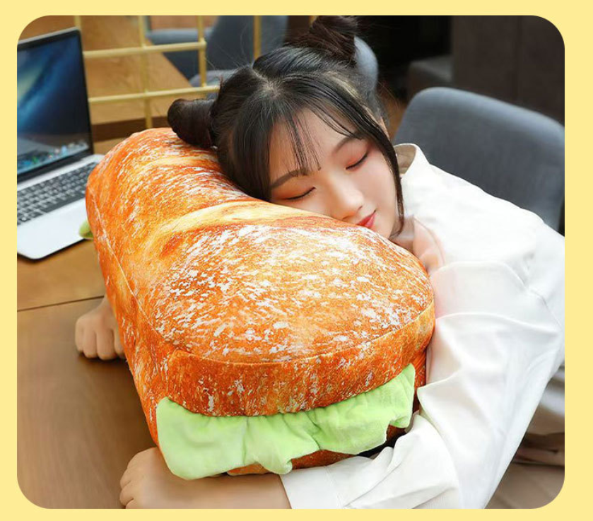 Person hugging a large sandwich-shaped pillow in an office setting