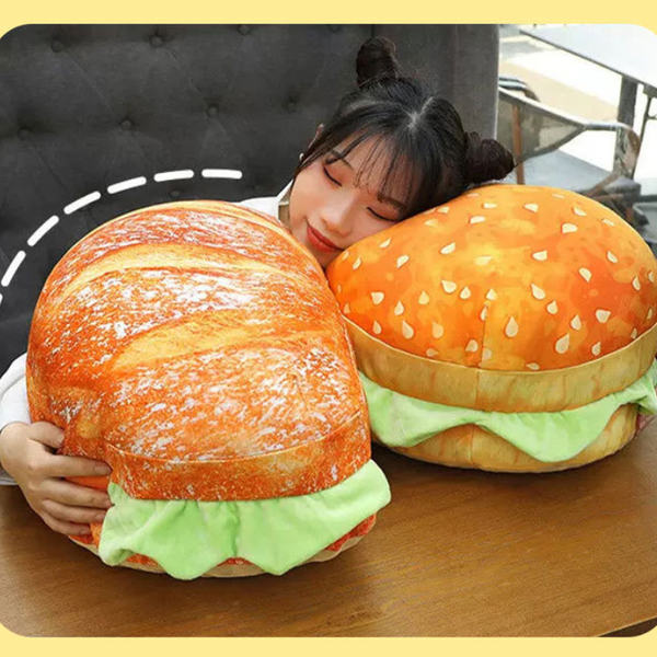 Person hugging a large plush burger and bread toy on a wooden table.