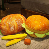 Hamburger-shaped plush toy with buns, lettuce, and a cherry on a textured surface.