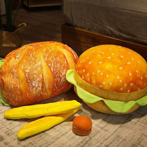 Hamburger-shaped plush toy with buns, lettuce, and a cherry on a textured surface.