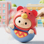 Toy with a red hat and blue body, held by a hand against a colorful background