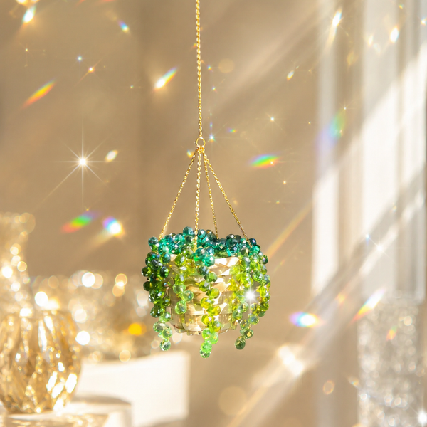Green beaded hanging ornament with a gold chain against a sparkling background