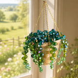 Hanging plant with green beads in front of a window with a view of a garden.