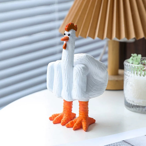 White goose figurine with orange feet and beak on a surface with a lamp and plant in the background.