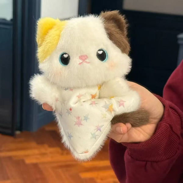 Plush toy resembling a cat held in a hand with a star-patterned blanket