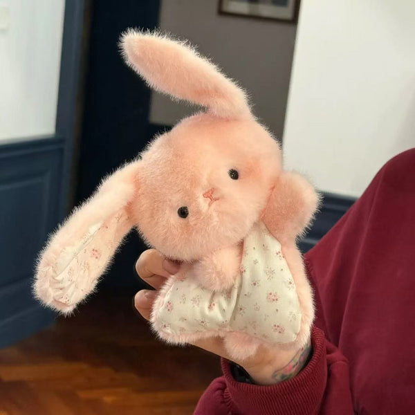 Pink plush bunny held by a person wearing a red sweater.
