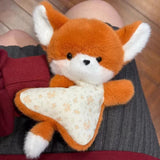Plush fox toy held by a person on a wooden floor.