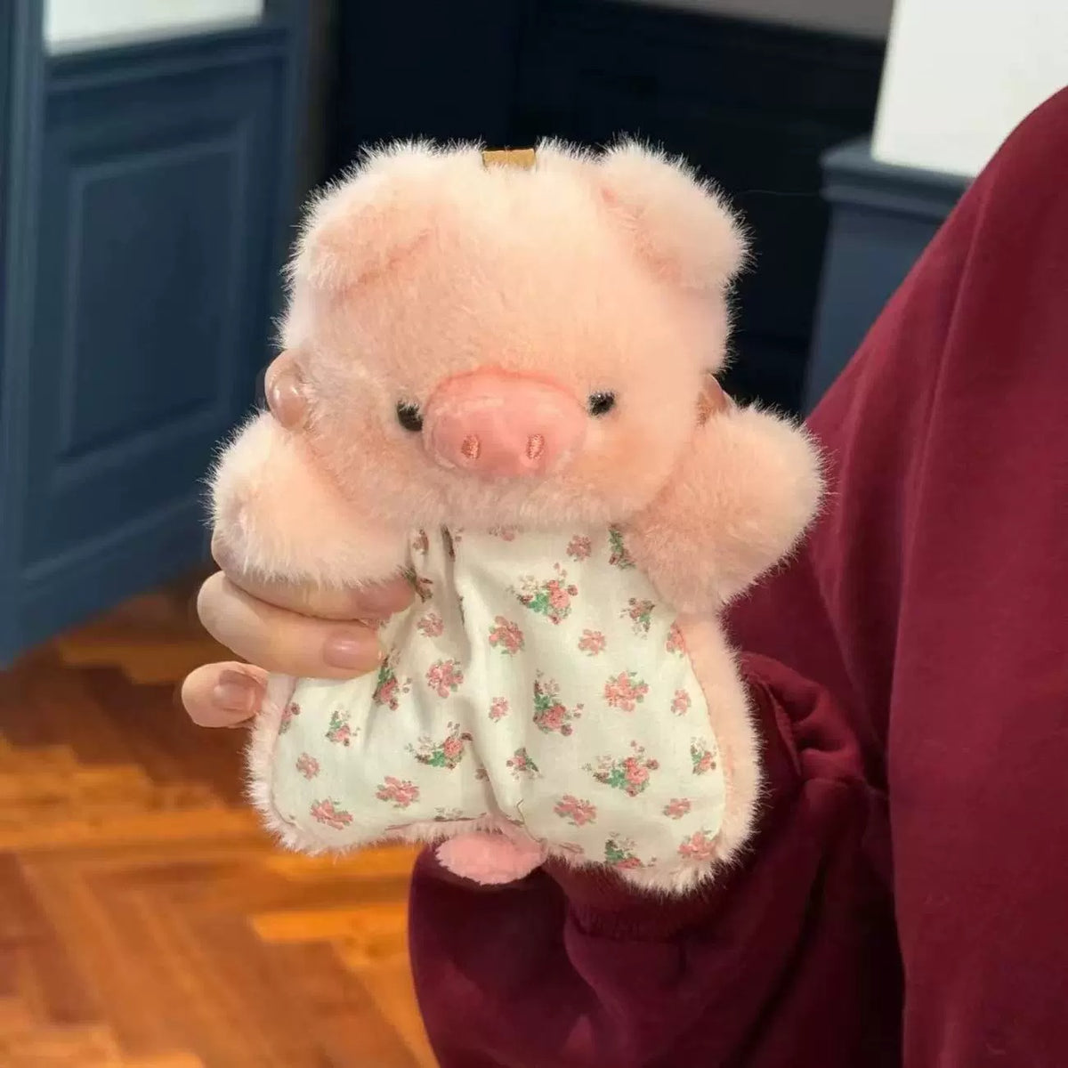 Person holding a pink plush pig toy with a floral patterned bag.
