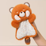 Plush toy red panda holding a small white blanket with floral pattern on a beige background
